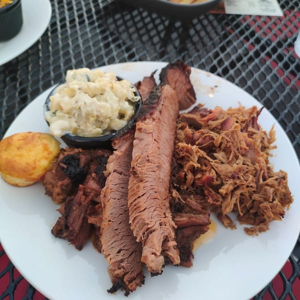 F325 BBQ plate with sliced brisket, pulled pork, macaroni and cheese, and a cornbread muffin.