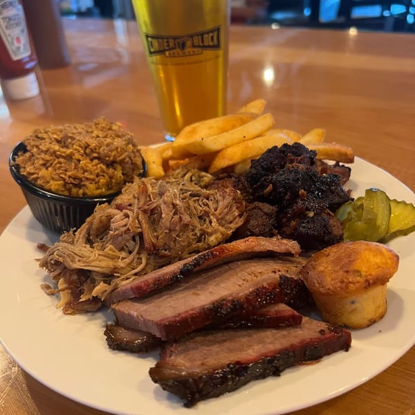 F325 BBQ platter with sliced brisket, pulled pork, burnt ends, fries, corn casserole, pickles, and cornbread.